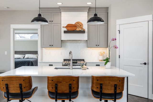 kitchen featuring gray cabinetry, decorative light fixtures, tasteful backsplash, and an island with sink