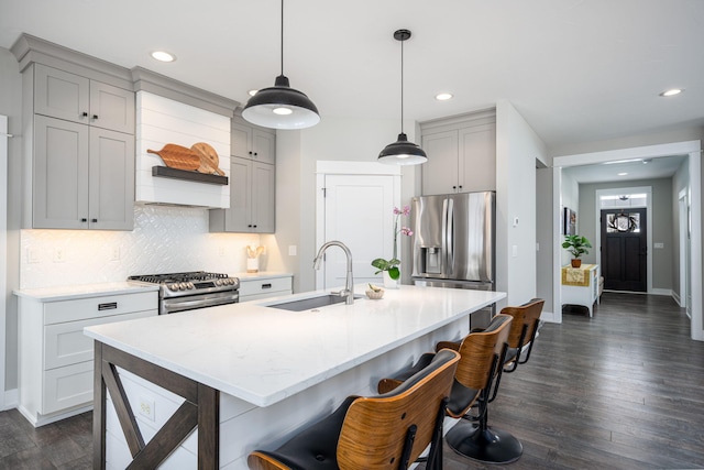 kitchen featuring sink, tasteful backsplash, appliances with stainless steel finishes, dark hardwood / wood-style flooring, and pendant lighting