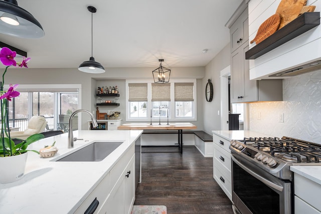 kitchen with sink, hanging light fixtures, dark hardwood / wood-style floors, tasteful backsplash, and stainless steel gas range oven