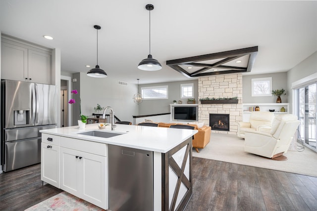 kitchen with dark hardwood / wood-style floors, sink, hanging light fixtures, a kitchen island with sink, and stainless steel appliances