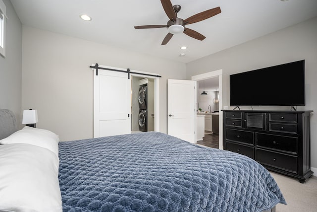 carpeted bedroom with sink, a barn door, and ceiling fan