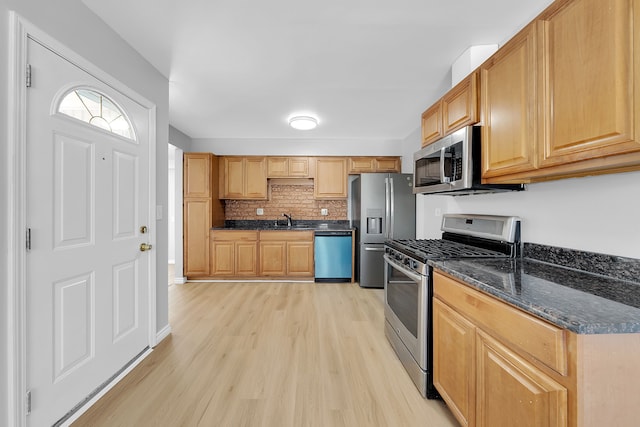 kitchen featuring sink, decorative backsplash, dark stone counters, light hardwood / wood-style floors, and stainless steel appliances