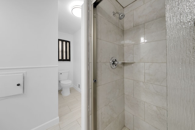 bathroom featuring a shower with door and toilet