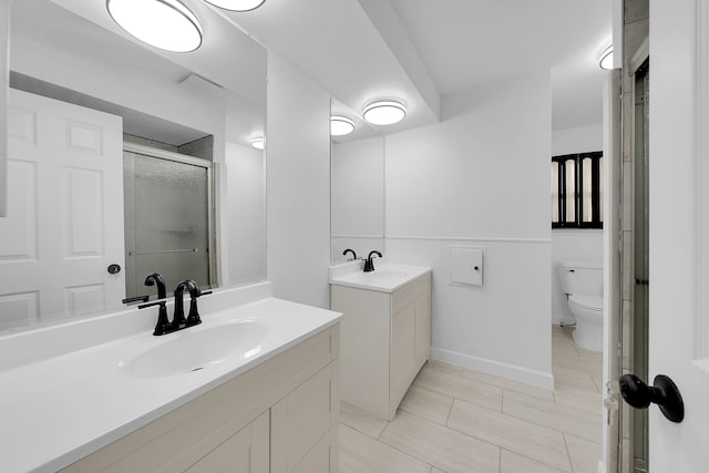 bathroom featuring vanity, a shower with door, and toilet