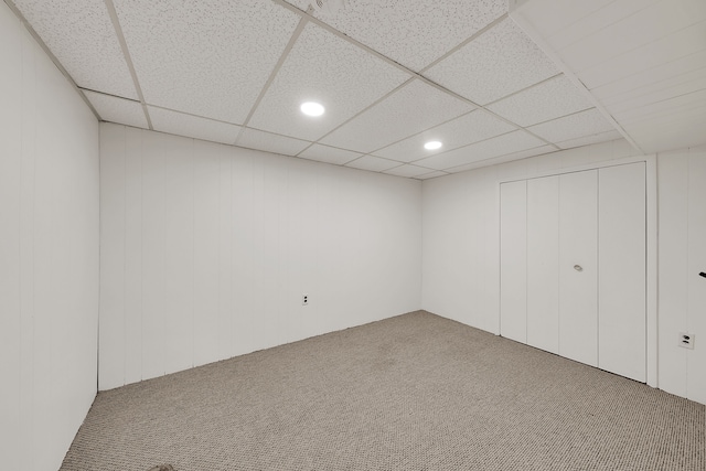 basement with a paneled ceiling and carpet