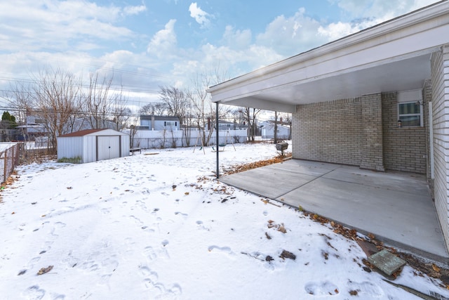 snowy yard featuring a shed