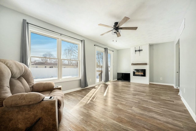 living room featuring hardwood / wood-style flooring, a large fireplace, and ceiling fan