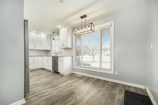 kitchen with tasteful backsplash, decorative light fixtures, light hardwood / wood-style flooring, appliances with stainless steel finishes, and white cabinets