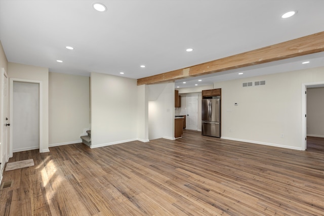 unfurnished living room with wood-type flooring and beam ceiling