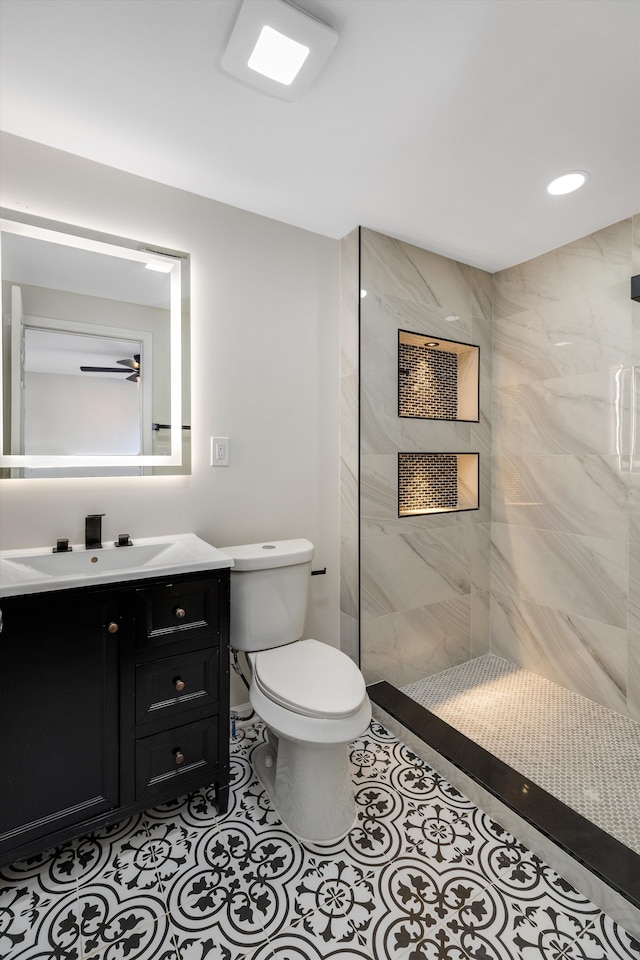 bathroom featuring vanity, tiled shower, tile patterned floors, and toilet