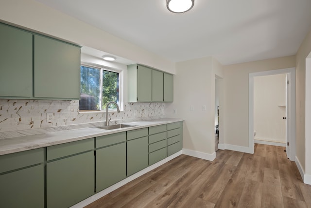 kitchen with sink, green cabinets, decorative backsplash, and light wood-type flooring