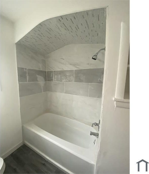 bathroom featuring tiled shower / bath, wood-type flooring, and toilet