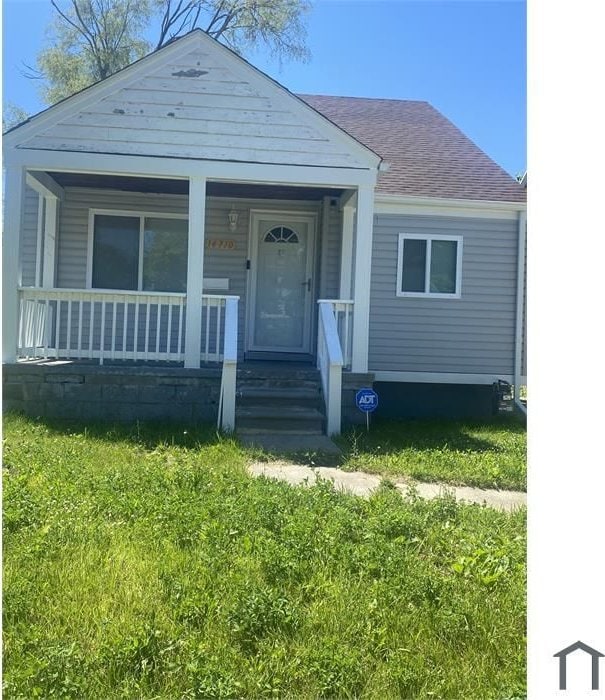 bungalow with a front yard and covered porch