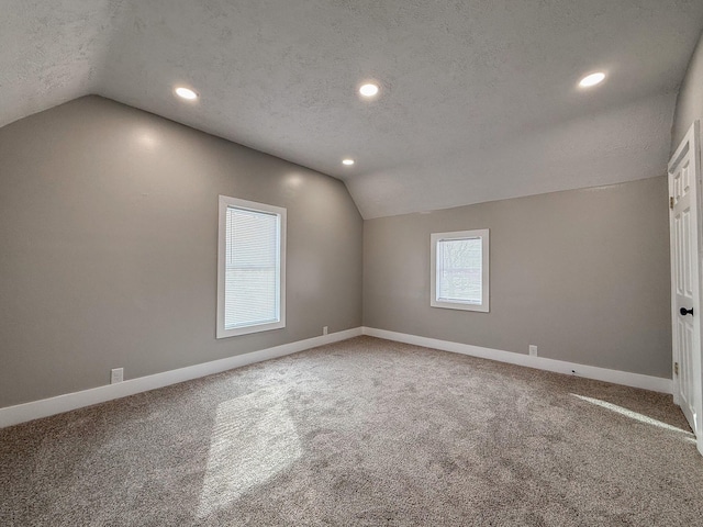 bonus room featuring vaulted ceiling, carpet, and a textured ceiling