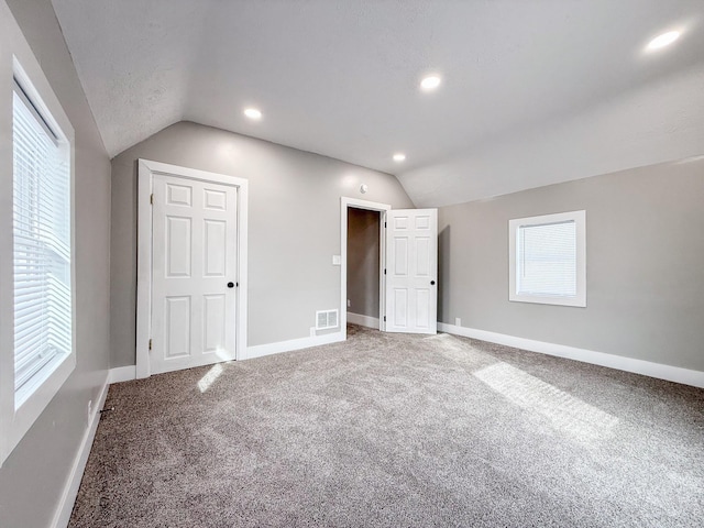 unfurnished bedroom featuring lofted ceiling and carpet floors