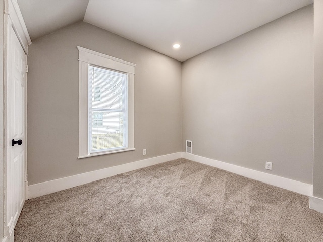 carpeted spare room with vaulted ceiling