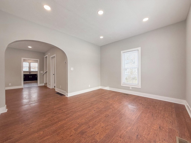 spare room featuring dark wood-type flooring and a textured ceiling