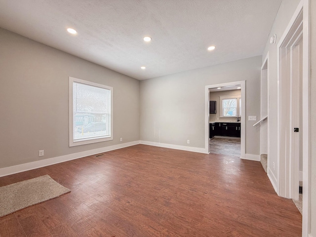 empty room with dark hardwood / wood-style floors and a textured ceiling