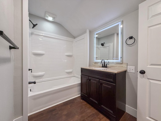 bathroom featuring wood-type flooring, lofted ceiling, vanity, and shower / bathing tub combination