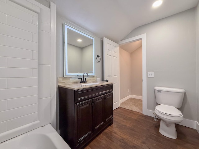 bathroom featuring vanity, hardwood / wood-style flooring, vaulted ceiling, and toilet