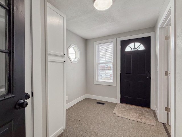 entrance foyer featuring light carpet and a textured ceiling