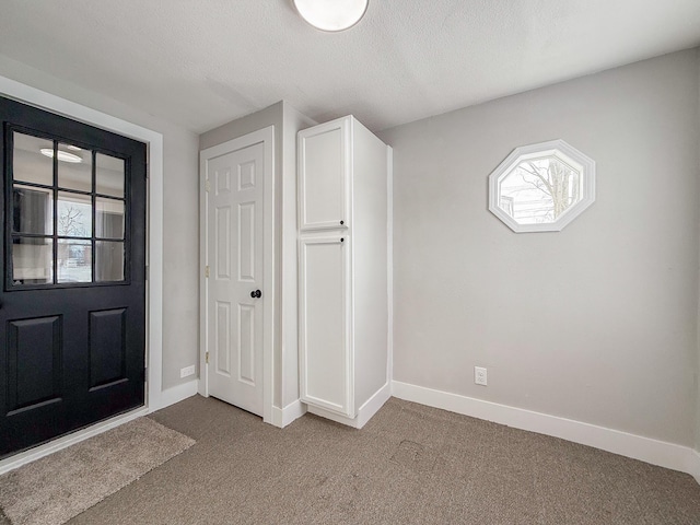 foyer featuring light colored carpet and a textured ceiling