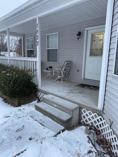 snow covered property entrance featuring a porch