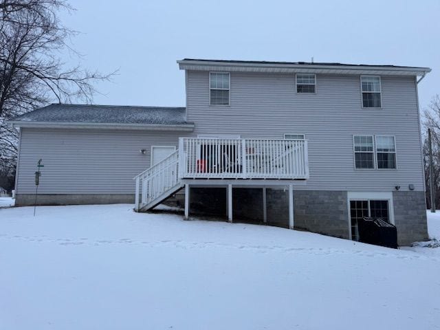 snow covered house featuring a wooden deck