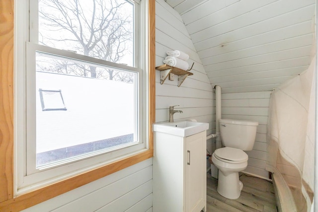 bathroom featuring toilet, lofted ceiling, vanity, and wooden walls