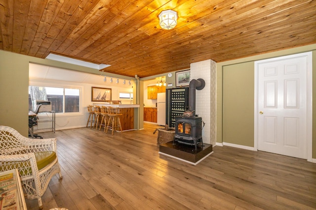 sitting room featuring bar area, wood ceiling, wood-type flooring, and a wood stove