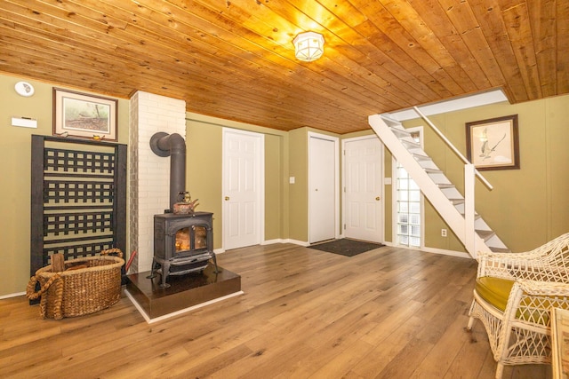 living area with hardwood / wood-style flooring, wooden ceiling, and a wood stove