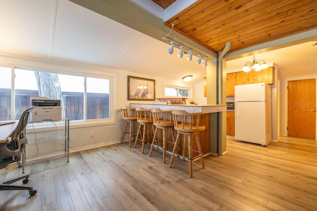 kitchen featuring light hardwood / wood-style floors, white fridge, a kitchen bar, and kitchen peninsula