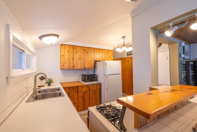 kitchen with pendant lighting, sink, stove, white refrigerator, and a chandelier