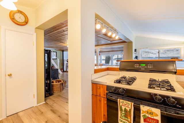 kitchen with crown molding, lofted ceiling, light wood-type flooring, and range with gas cooktop