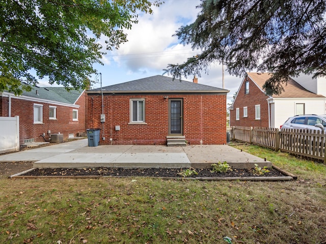 rear view of property featuring central AC unit, a patio area, and a lawn