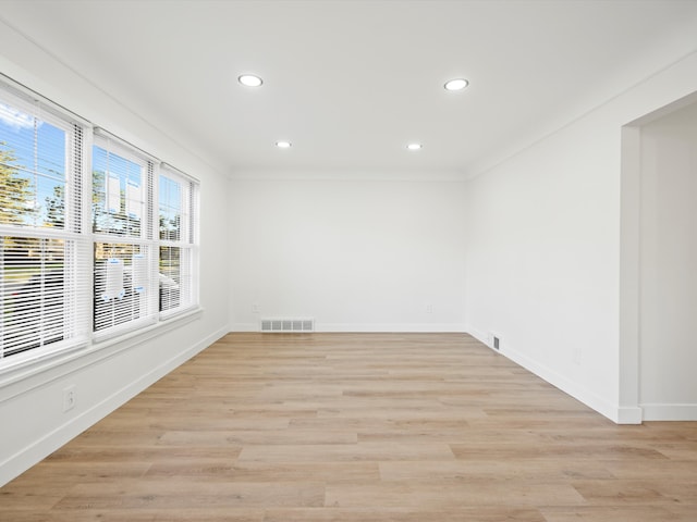 empty room with crown molding and light wood-type flooring