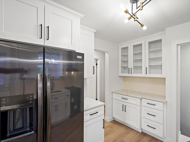 kitchen with light stone counters, stainless steel fridge, light wood-type flooring, and white cabinets