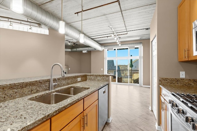 kitchen with appliances with stainless steel finishes, rail lighting, sink, hanging light fixtures, and light stone counters