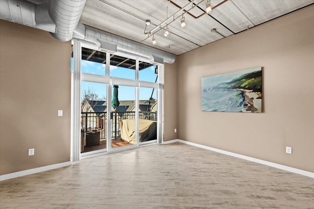 empty room with hardwood / wood-style flooring and rail lighting