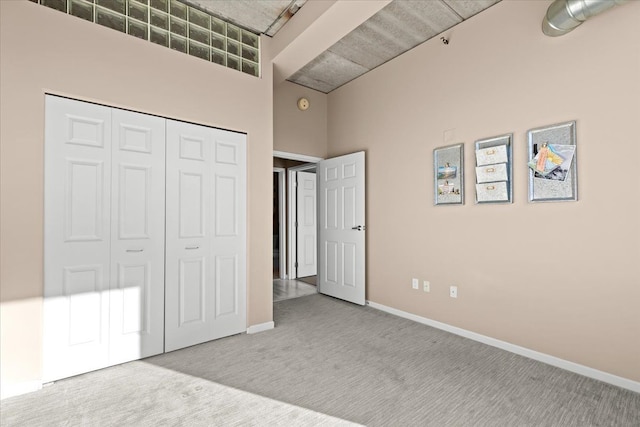 unfurnished bedroom featuring a high ceiling, light carpet, and a closet