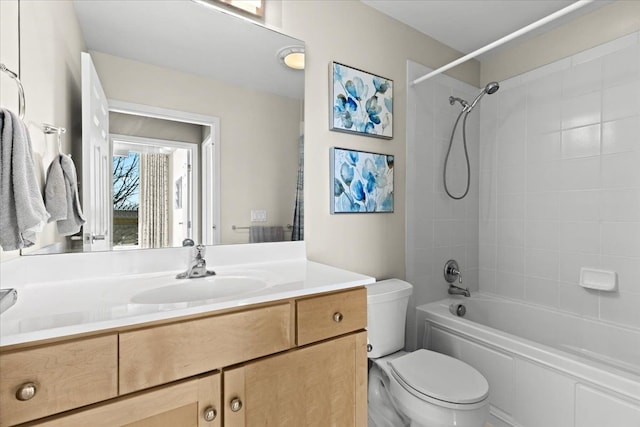 full bathroom featuring tiled shower / bath, vanity, and toilet