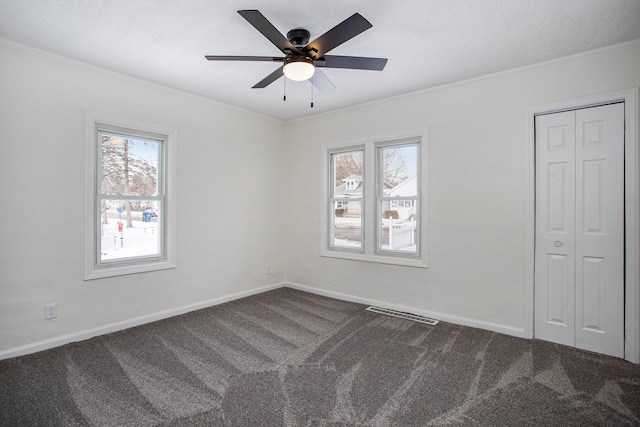 carpeted empty room with a wealth of natural light and ornamental molding