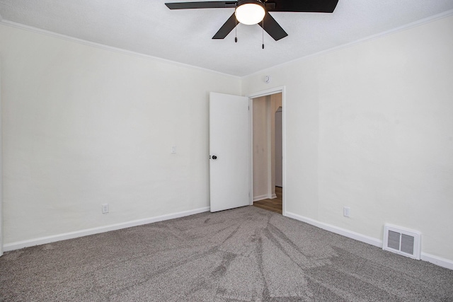 empty room with crown molding, ceiling fan, and carpet flooring