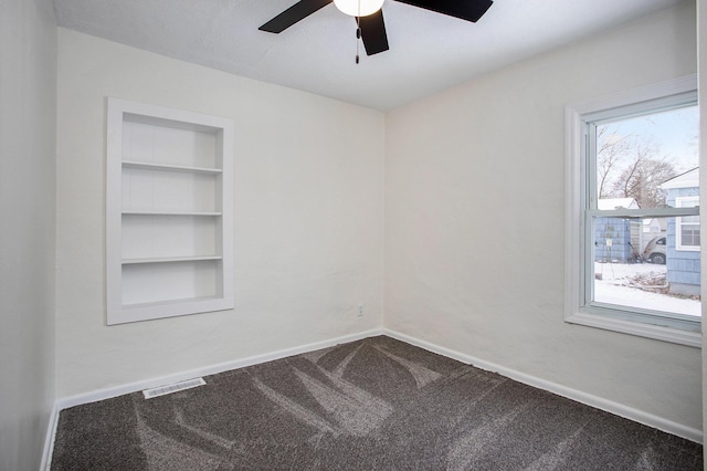 empty room with built in shelves, ceiling fan, and carpet