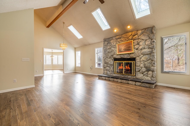 unfurnished living room with high vaulted ceiling, hardwood / wood-style floors, beamed ceiling, a fireplace, and ceiling fan with notable chandelier