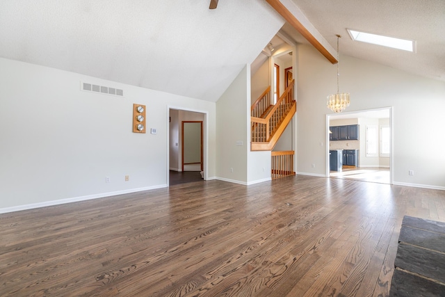 unfurnished living room with dark hardwood / wood-style floors, high vaulted ceiling, a skylight, beamed ceiling, and an inviting chandelier