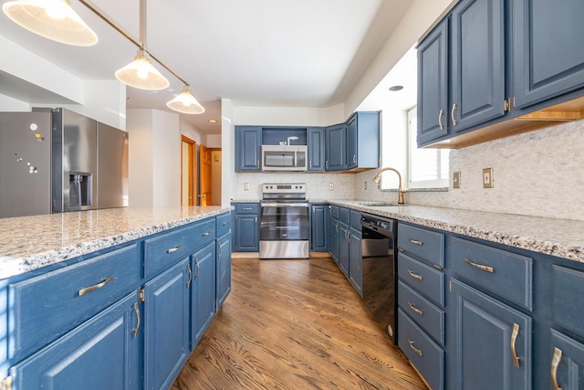 kitchen with blue cabinets, appliances with stainless steel finishes, sink, and hanging light fixtures