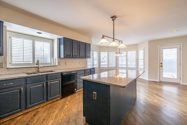 kitchen with sink, light stone counters, a center island, dishwasher, and pendant lighting