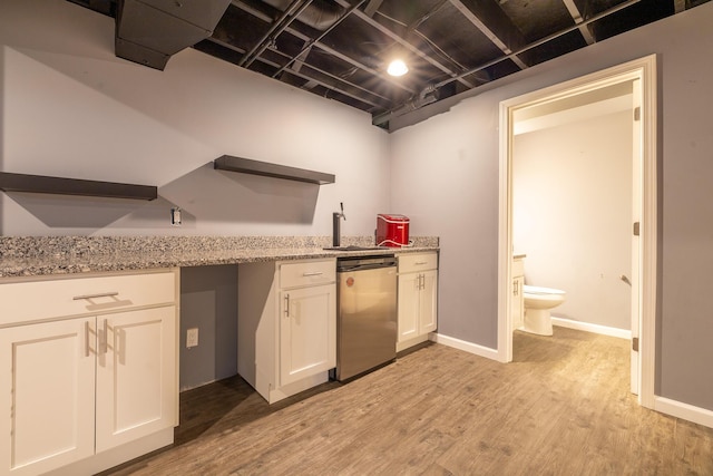 kitchen with sink, light stone countertops, light hardwood / wood-style floors, white cabinets, and stainless steel dishwasher