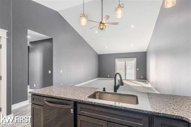 kitchen with sink, vaulted ceiling, dishwasher, pendant lighting, and light stone countertops